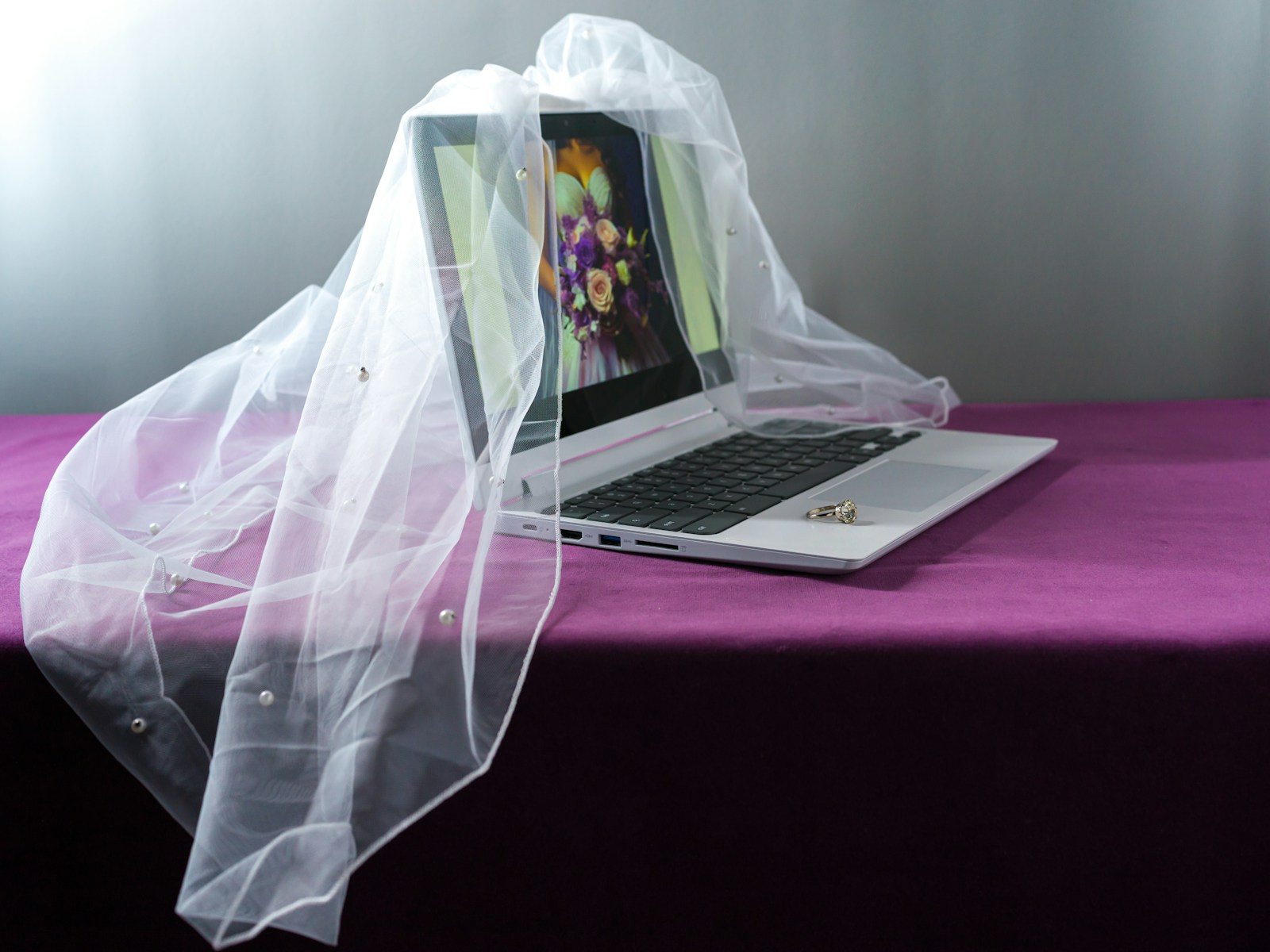 A laptop wears a wedding veil.